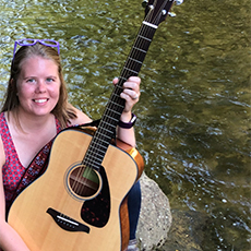 Author Beebe holding a guitar by the lake